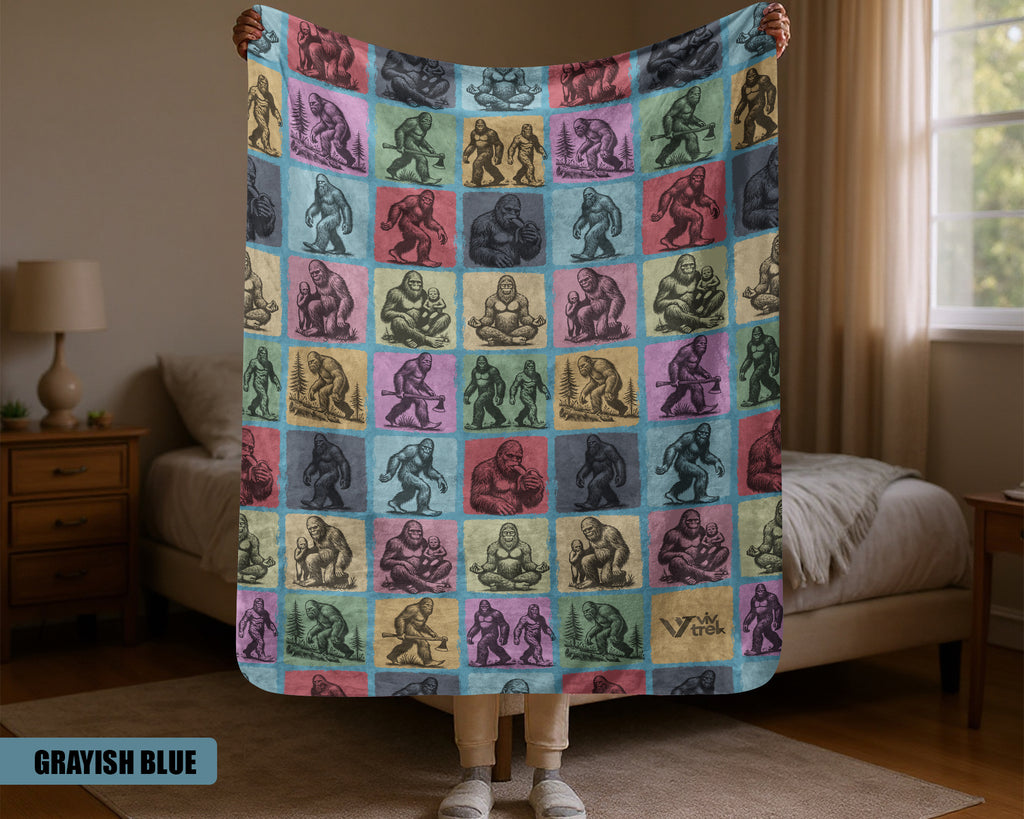 Person holding a colorful blanket with various Bigfoot illustrations in a bedroom setting.