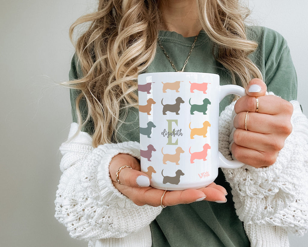 Person holding a mug with colorful dachshund patterns and the name