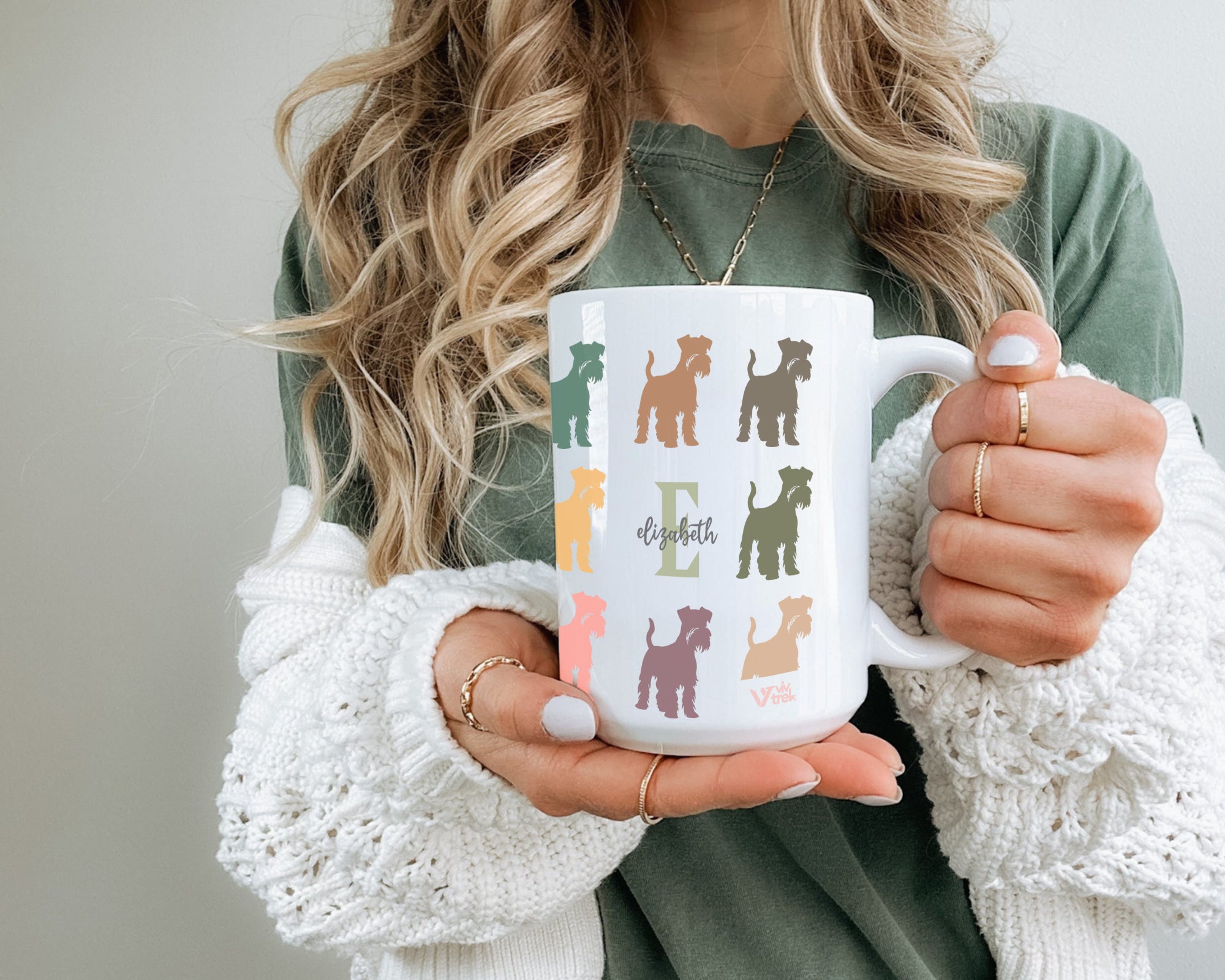 Person holding a mug with colorful dog illustrations and initial name text