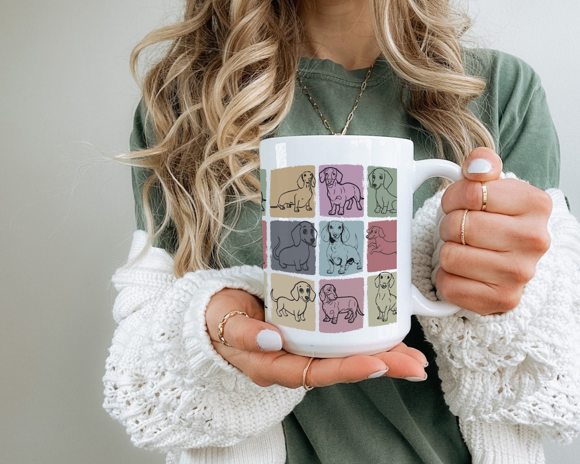 Person holding a mug with dog illustrations on a plain background
