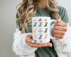 Person holding a mug with dog pattern and initial name text