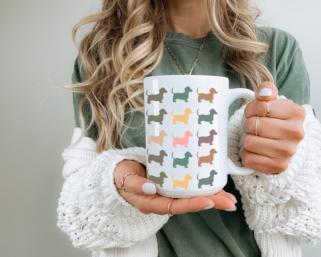 Person holding a white mug with colorful dog pattern