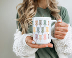 Person holding a white mug with colorful pattern against a neutral background